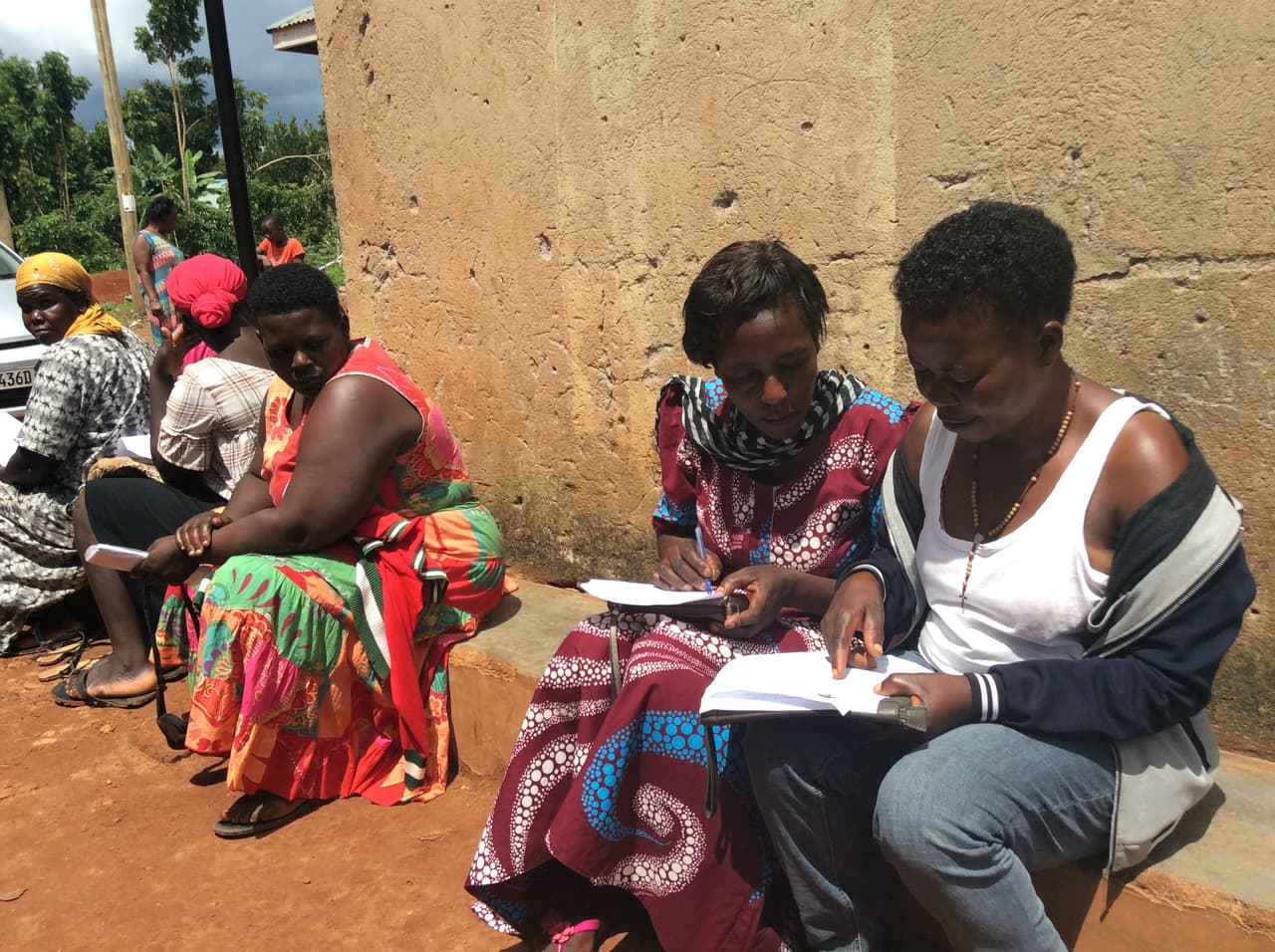 Group members going through their record books together at a JumpStart Africa meeting.